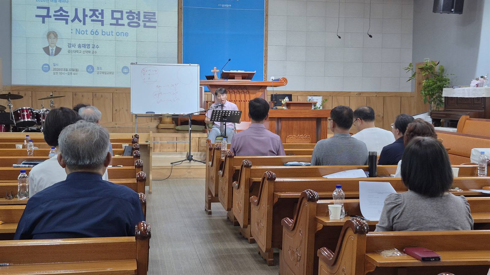 강단 옆 화면에 “구속사적 모형론” 세미나 안내가 띄워진 본당